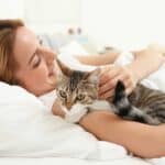 Katze mit Frau im Bett kuscheln (depositphotos.com)